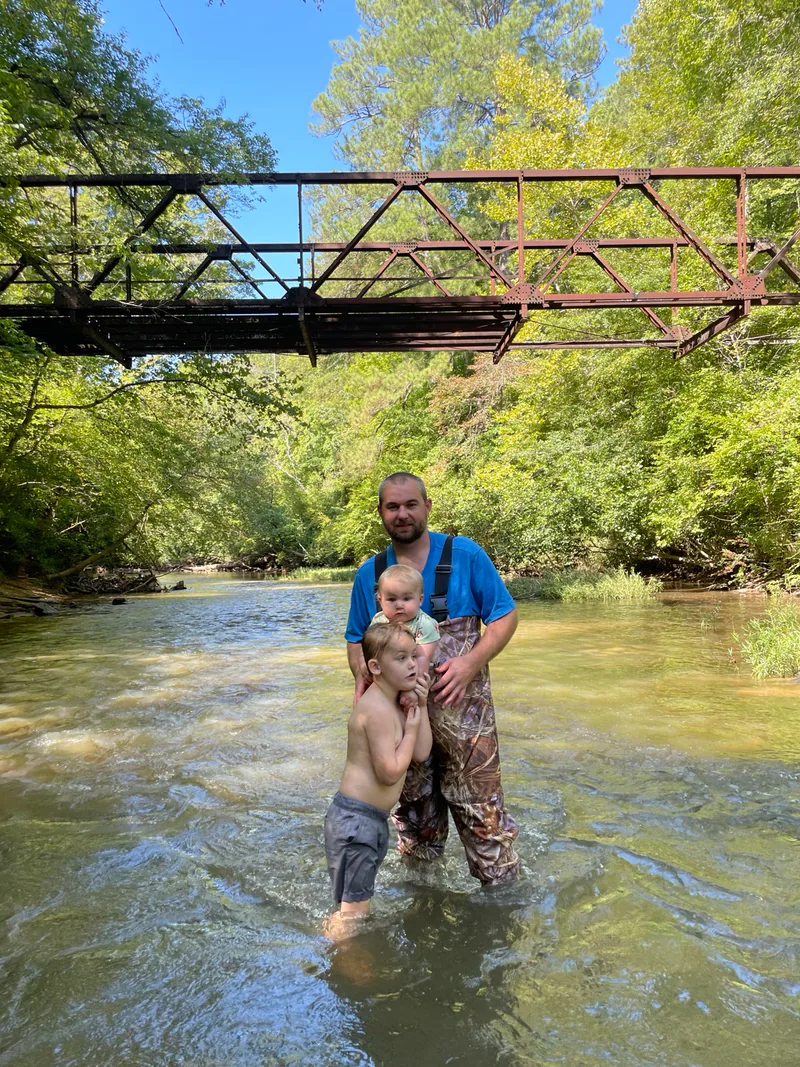 Daniel with Austin and Noah in the Tallapoosa River beneath the old bridge between their Hipcamp properties.