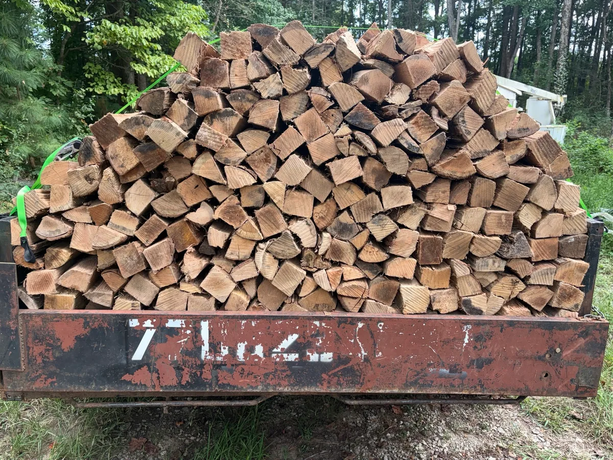 Split firewood stacked on a utility trailer, viewed from the rear