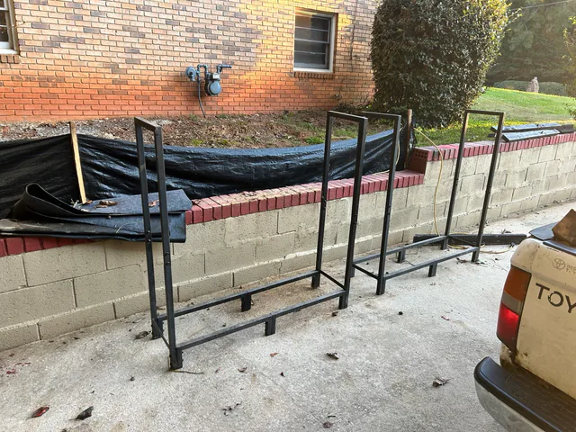 Two empty metal racks beside a low retaining wall