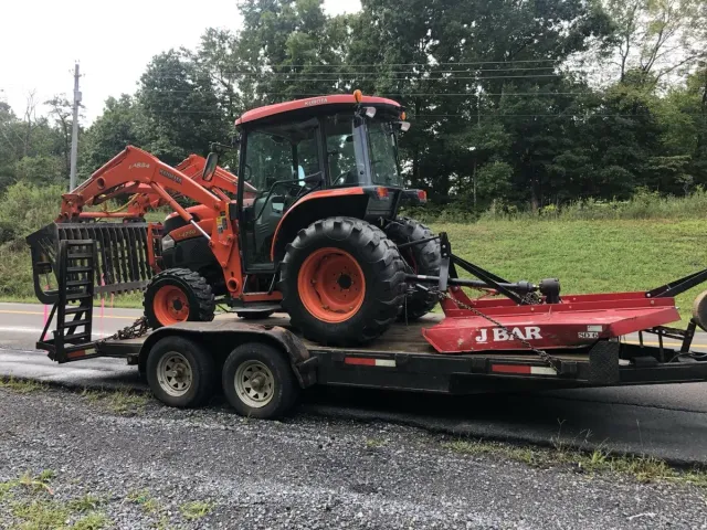 Moss and Sons Kubota tractor with a front loader and rear rotary cutter on its equipment trailer